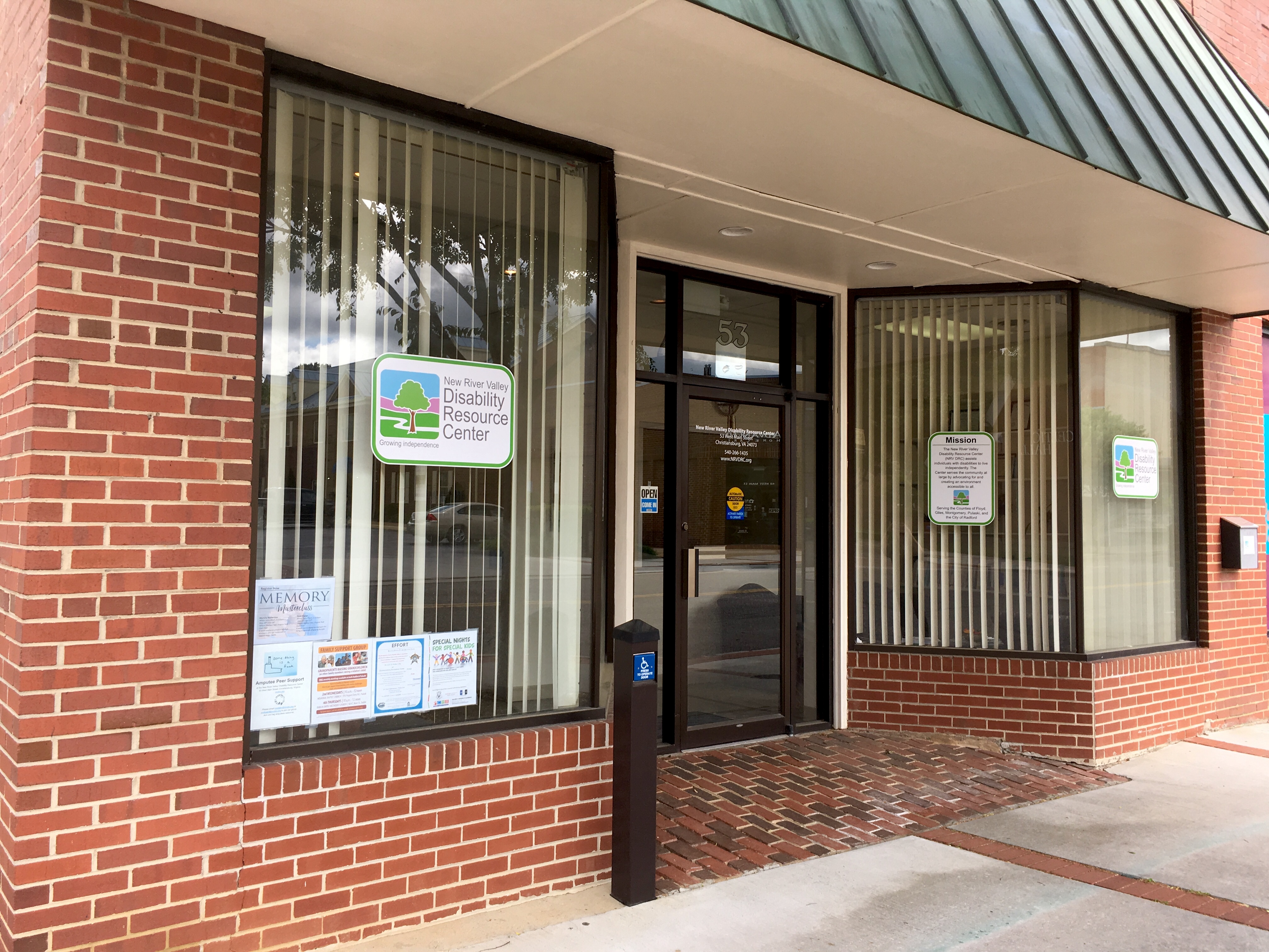 Red brick building storefront with NRV DRC logo signs in the windows.